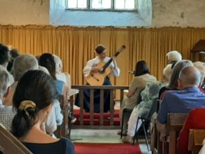 A photo of classcal guitarist Hope Cramsie performing for at St Mary's Church, Craswall in August 2022
